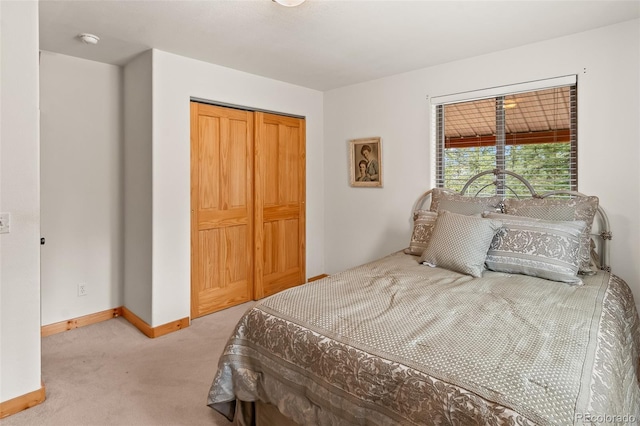 bedroom with baseboards, a closet, and light colored carpet