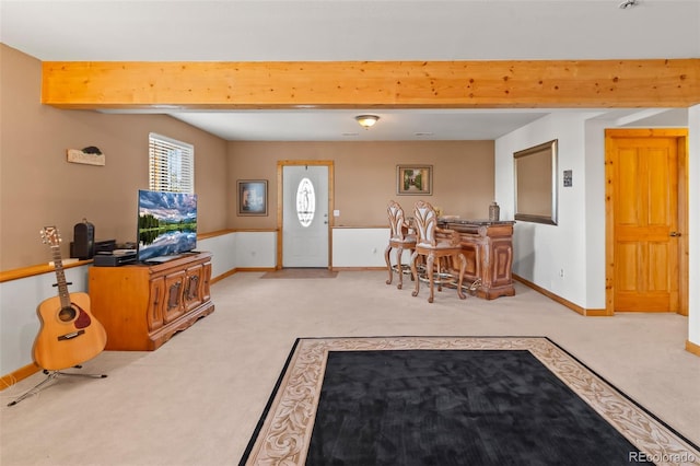 interior space with beam ceiling, light carpet, and baseboards