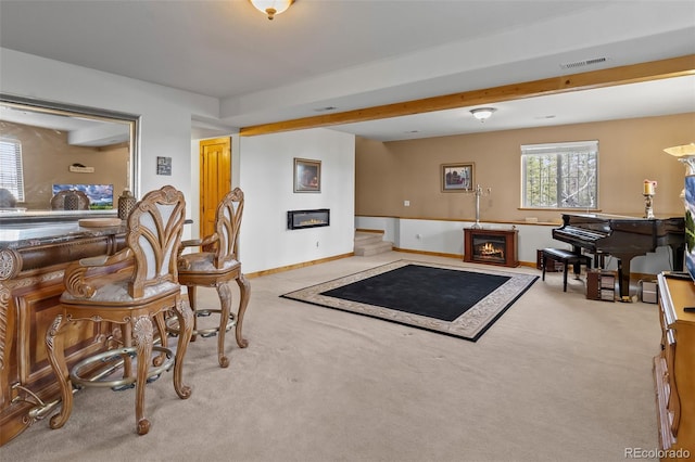 living room with baseboards, a glass covered fireplace, and light colored carpet