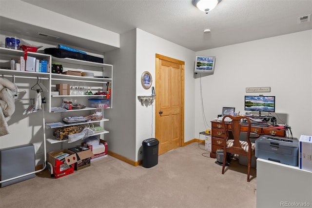 carpeted office with a textured ceiling, baseboards, and visible vents