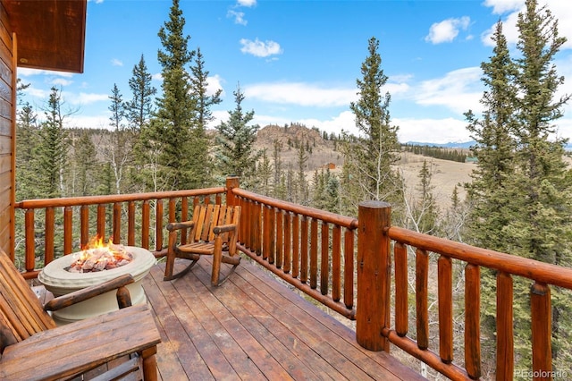 wooden terrace with a fire pit and a mountain view