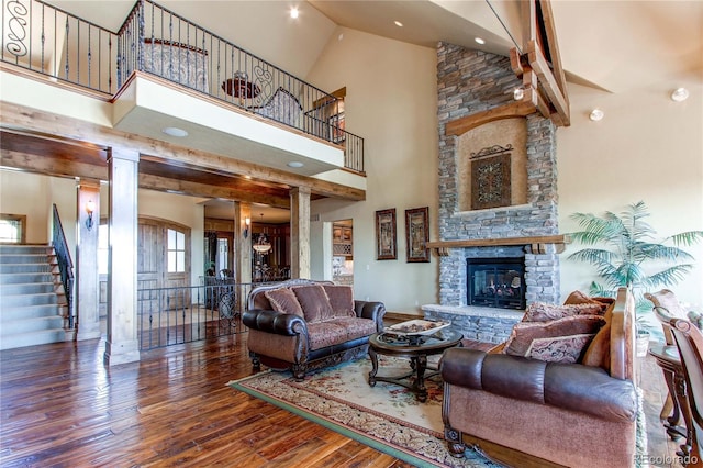 living room featuring high vaulted ceiling, decorative columns, a fireplace, and hardwood / wood-style floors