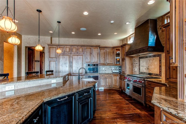 kitchen with pendant lighting, dark wood-type flooring, custom range hood, double oven range, and light stone countertops