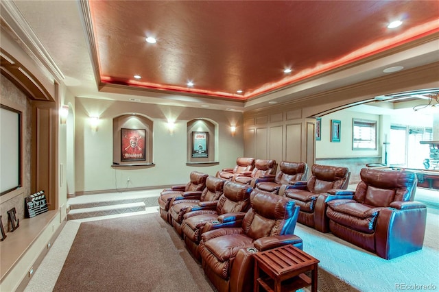 carpeted cinema with a raised ceiling and crown molding