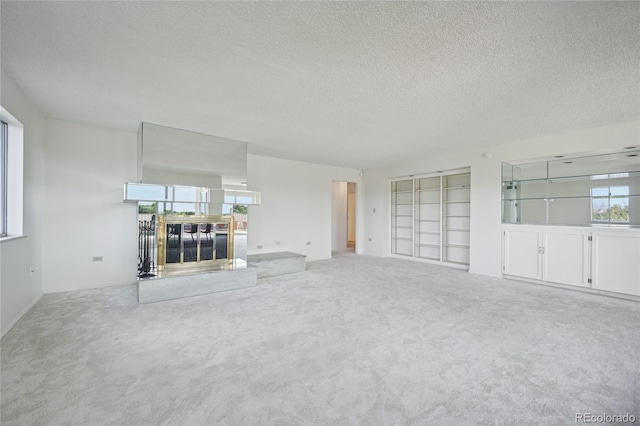 unfurnished living room with carpet flooring, built in features, and a textured ceiling