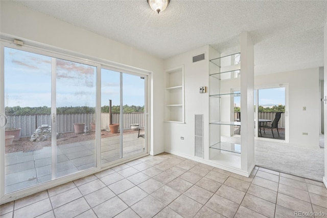 unfurnished room featuring light tile patterned flooring, built in features, and a textured ceiling