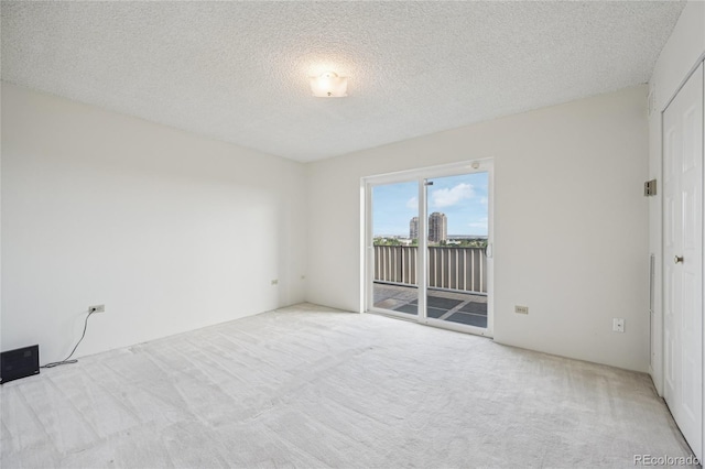 empty room with a textured ceiling and light carpet