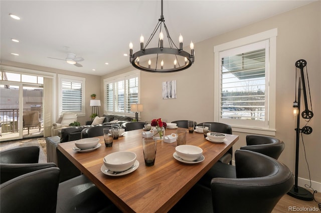 dining area featuring hardwood / wood-style floors, ceiling fan with notable chandelier, and plenty of natural light