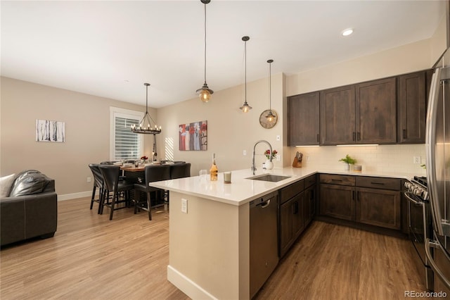 kitchen with kitchen peninsula, sink, stainless steel appliances, and light wood-type flooring