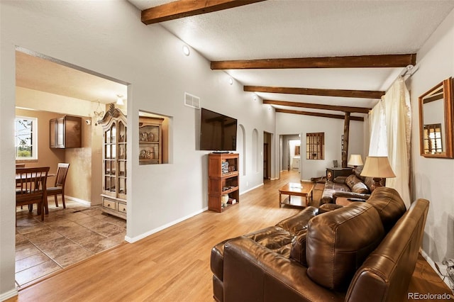 living room with a textured ceiling, hardwood / wood-style floors, and vaulted ceiling with beams