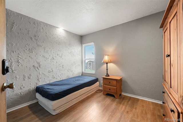 bedroom with a textured ceiling and light wood-type flooring