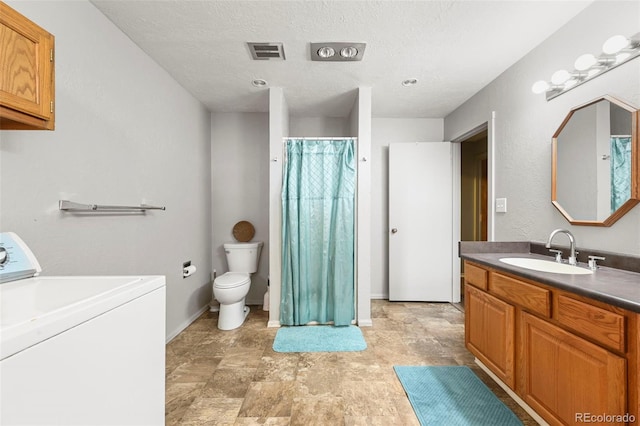 bathroom with vanity, toilet, a textured ceiling, and washer / clothes dryer