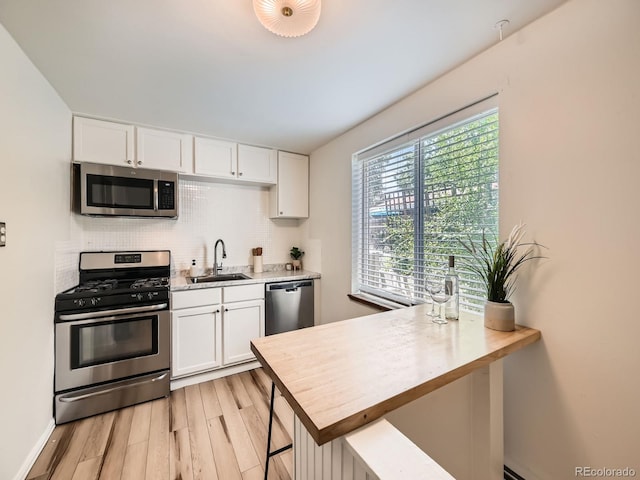 4418 W 11th Ave, Denver, CO 80204 - kitchen with appliances with stainless steel finishes, light countertops, light wood-style floors, decorative backsplash, and white cabinets