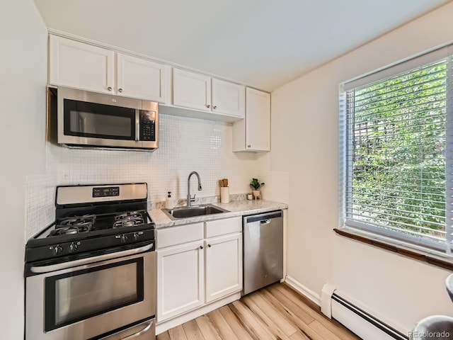 4418 W 11th Ave, Denver, CO 80204 - kitchen featuring appliances with stainless steel finishes, a baseboard heating unit, healthy amount of natural light, and backsplash
