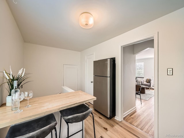 4418 W 11th Ave, Denver, CO 80204 - kitchen with freestanding refrigerator, light wood finished floors, a breakfast bar, and wooden counters