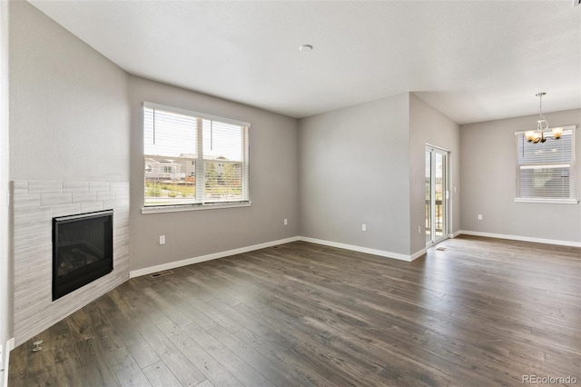 14259 Beebalm Ave, Parker, CO 80134 - unfurnished living room featuring a chandelier, a tile fireplace, healthy amount of natural light, and dark wood-style flooring