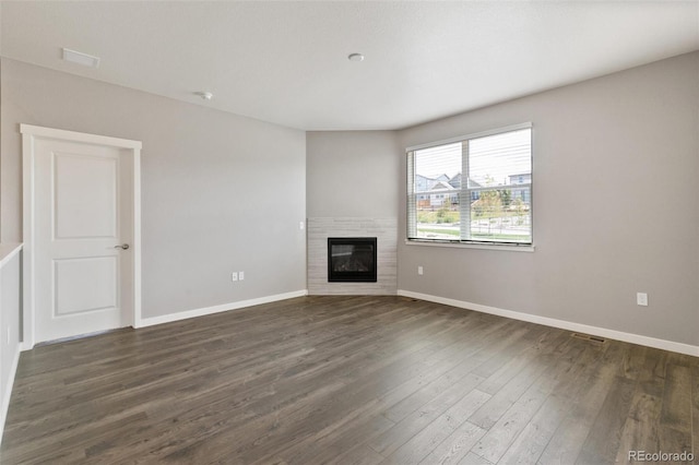14259 Beebalm Ave, Parker, CO 80134 - unfurnished living room featuring dark wood-type flooring, a glass covered fireplace, and baseboards
