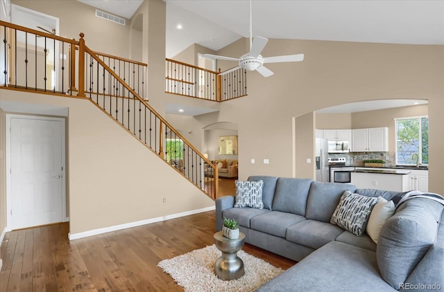 living room featuring high vaulted ceiling, ceiling fan, and light hardwood / wood-style floors