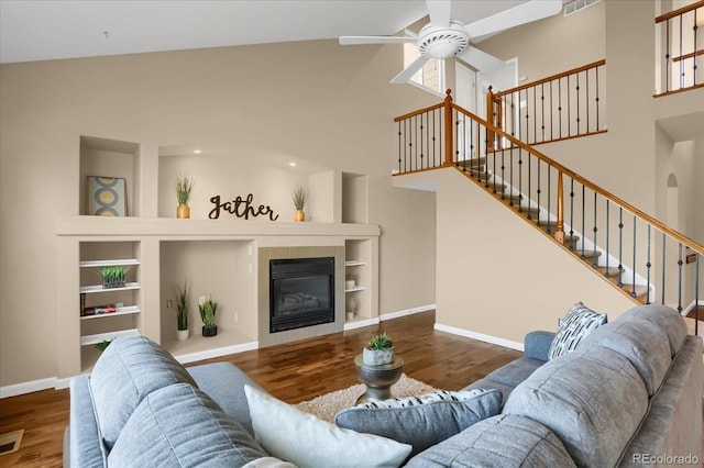 living room with high vaulted ceiling, ceiling fan, a tile fireplace, and dark hardwood / wood-style floors