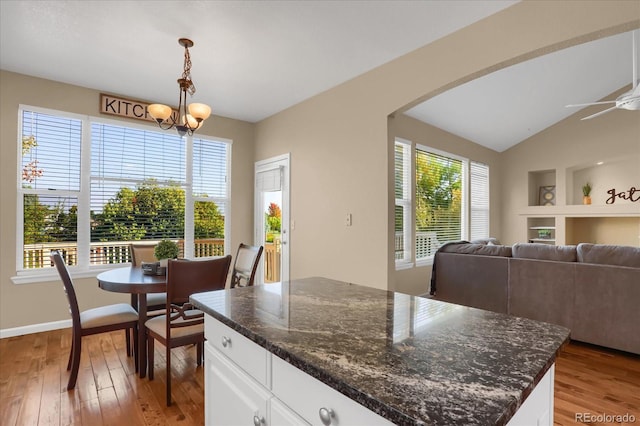 kitchen with a center island, light hardwood / wood-style floors, pendant lighting, dark stone counters, and white cabinetry