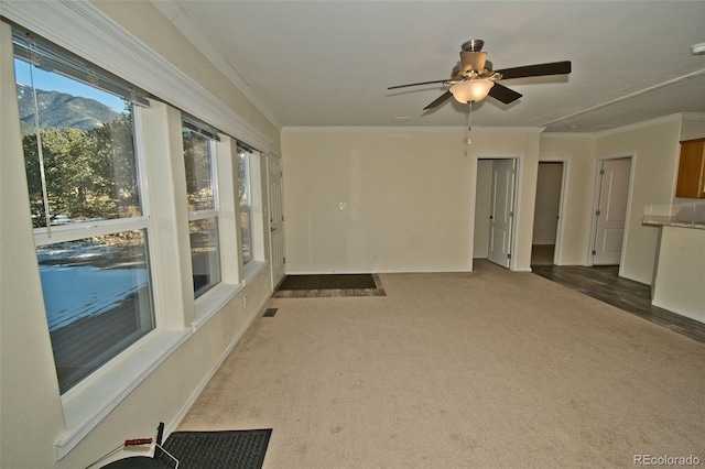 interior space with ceiling fan, carpet, a mountain view, and ornamental molding