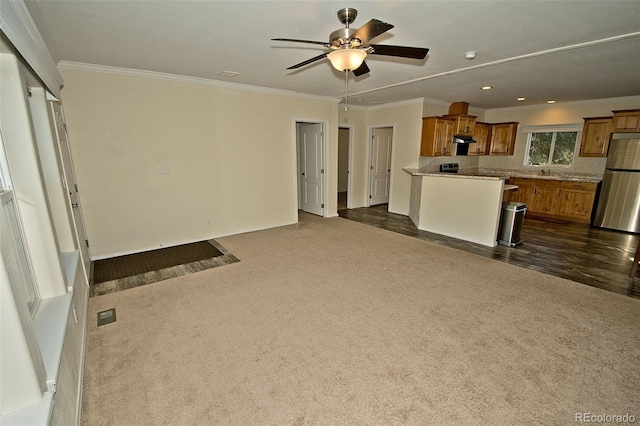 unfurnished living room with ceiling fan, dark carpet, and ornamental molding