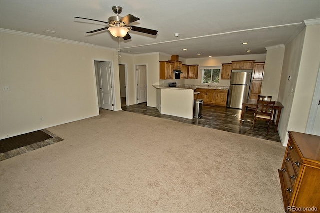 unfurnished living room featuring ceiling fan, ornamental molding, and dark colored carpet