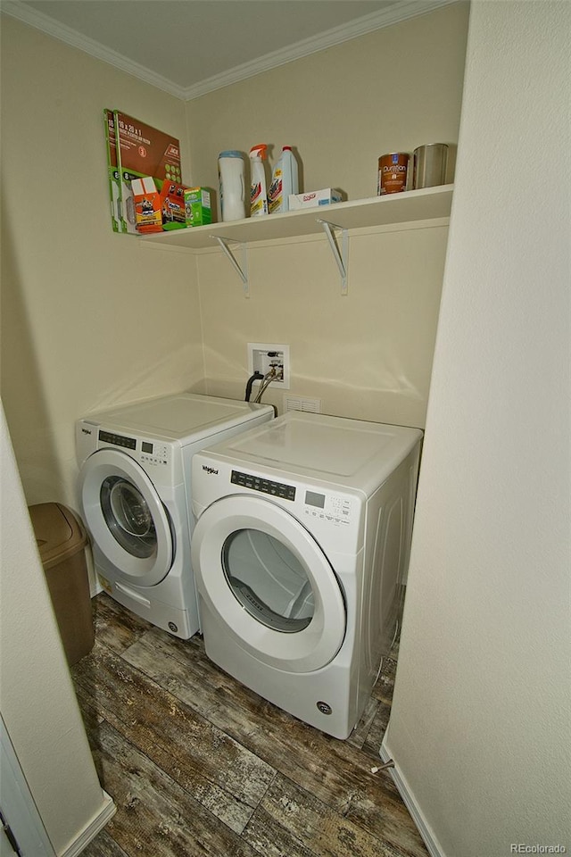 clothes washing area with ornamental molding, washer and clothes dryer, and dark hardwood / wood-style flooring