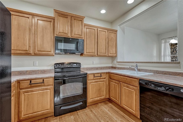 kitchen featuring light wood-type flooring, pendant lighting, sink, and black appliances