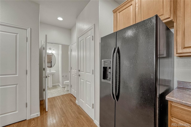 kitchen with black fridge, light brown cabinets, light hardwood / wood-style floors, and sink