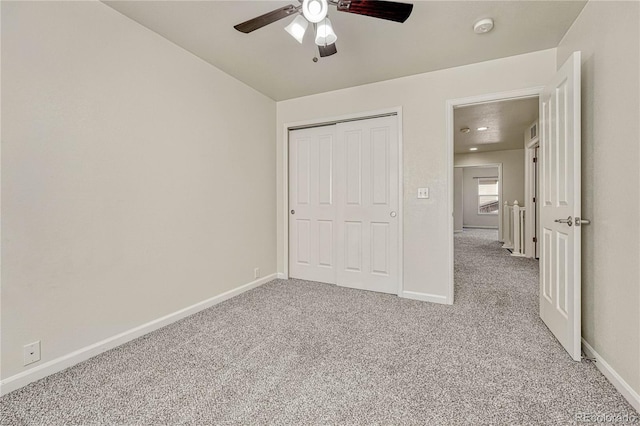 unfurnished bedroom featuring ceiling fan, a closet, and light colored carpet