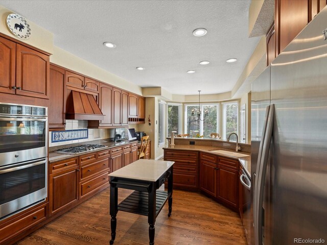 5700 S Benton Cir, Littleton, CO 80123 - kitchen with appliances with stainless steel finishes, a sink, a peninsula, custom range hood, and recessed lighting