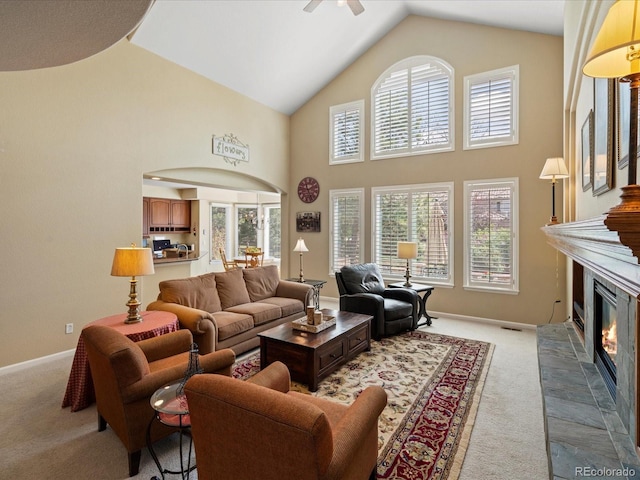 5700 S Benton Cir, Littleton, CO 80123 - carpeted living room featuring a ceiling fan, a glass covered fireplace, healthy amount of natural light, high vaulted ceiling, and baseboards