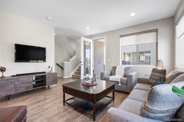 living room featuring stairs, light wood-style flooring, and a wealth of natural light