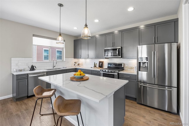 kitchen featuring decorative backsplash, light stone countertops, a center island, a sink, and stainless steel appliances