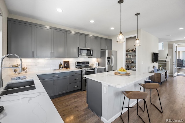 kitchen featuring light stone counters, a sink, dark wood-style floors, and stainless steel appliances