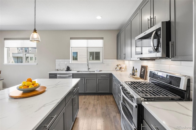 kitchen featuring appliances with stainless steel finishes, a sink, gray cabinets, recessed lighting, and backsplash