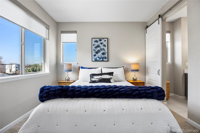 bedroom with baseboards and a barn door
