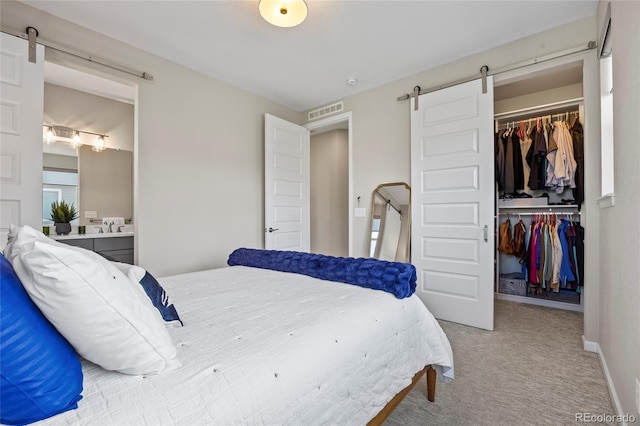 bedroom featuring visible vents, a barn door, a walk in closet, and a closet