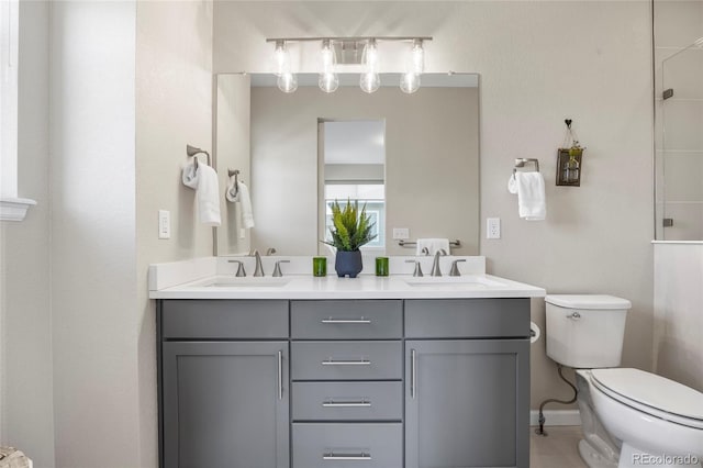 bathroom with double vanity, a sink, and toilet