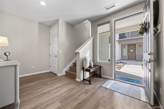 foyer with visible vents, wood finished floors, baseboards, stairway, and recessed lighting