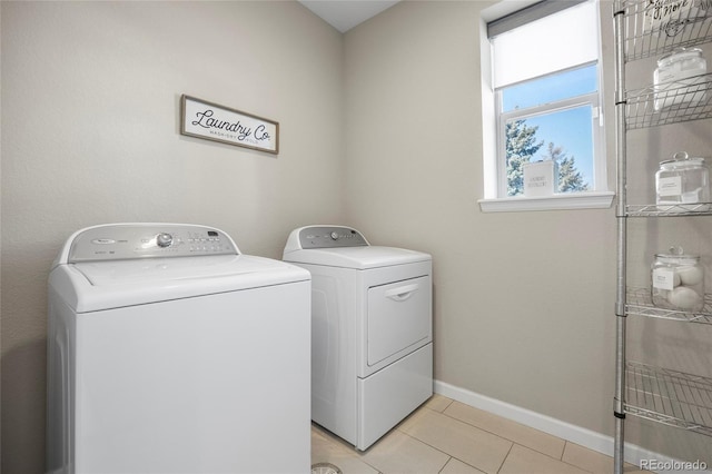 laundry room featuring laundry area, baseboards, light tile patterned floors, and washing machine and dryer