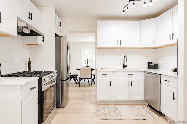1361 W Custer Pl, Denver, CO 80223 - kitchen featuring stainless steel appliances, under cabinet range hood, light wood-type flooring, and tasteful backsplash