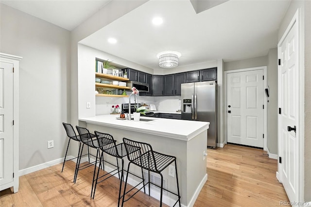 1325 W 112th Ave Unit B, Westminster, CO 80234 - kitchen with stainless steel appliances, light countertops, a kitchen breakfast bar, a peninsula, and open shelves