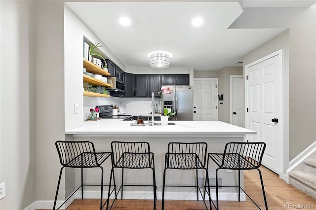 1325 W 112th Ave Unit B, Westminster, CO 80234 - kitchen with appliances with stainless steel finishes, light countertops, open shelves, a peninsula, and light wood finished floors