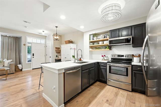 1325 W 112th Ave Unit B, Westminster, CO 80234 - kitchen with stainless steel appliances, a peninsula, light wood finished floors, light countertops, and open shelves