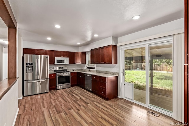 3735 S Lewiston St, Aurora, CO 80013 - kitchen with appliances with stainless steel finishes, wood finished floors, recessed lighting, and light stone countertops