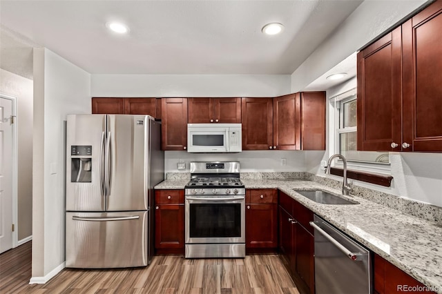 3735 S Lewiston St, Aurora, CO 80013 - kitchen with appliances with stainless steel finishes, light wood-style flooring, light stone counters, recessed lighting, and reddish brown cabinets