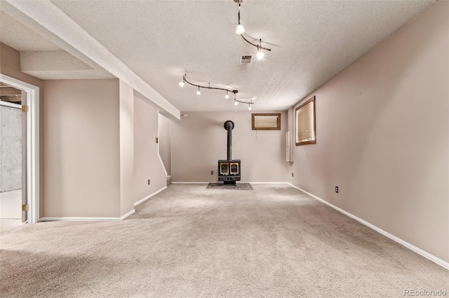 3735 S Lewiston St, Aurora, CO 80013 - basement featuring a wood stove, carpet, a textured ceiling, and rail lighting
