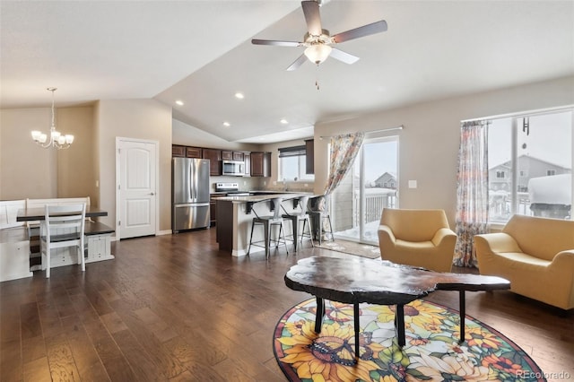 living room with ceiling fan with notable chandelier, dark wood-type flooring, and lofted ceiling